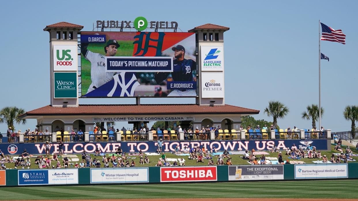 Fans enjoy a sunny day on a hill behind the left field fence before watching a spring baseball game between the Tigers and the Yankees, Monday, March 28, 2022, in Lakeland, Fla.