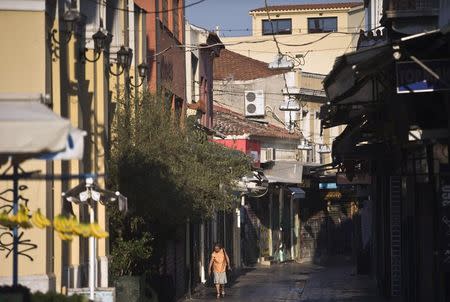 A woman makes her way at a main commercial street at the Monastiraki area in early morning before shops open in central Athens, Greece July 27, 2015. REUTERS/Ronen Zvulun