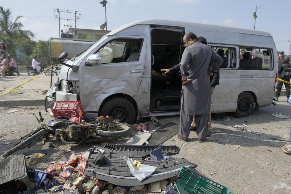 CORRECTS DATE - Pakistani investigators examine a damaged van at the site of a suicide attack in Karachi, Pakistan, Friday, April 19, 2024. Five Japanese nationals traveling in a van narrowly escaped a suicide attack when a suicide bomber detonated his explosive-laden vest near their vehicle in Pakistan's port city of Karachi on Friday, wounding three passers-by, police said. (AP Photo/Fareed Khan)