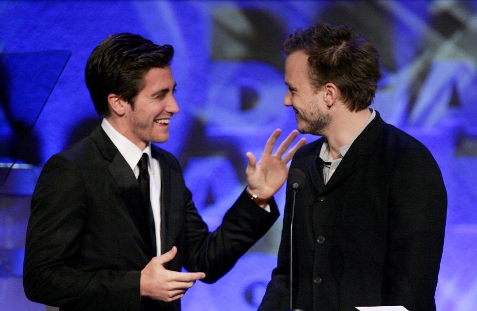 Jake and Health smiling at each other onstage in front of a microphone