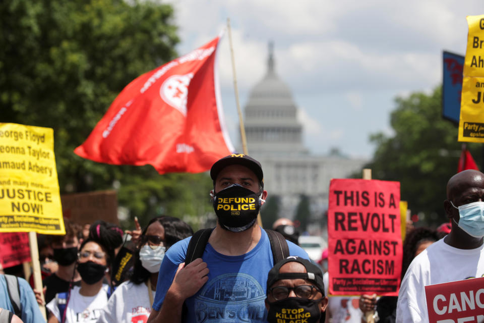 A demonstrator wears a protective face mask reading 