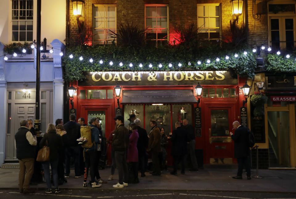 FILE - In this March 17, 2020 file photo people stand drinking outside the Coach & Horses pub on Saint Patrick's Day in the Covent Garden district of central London, which is a popular tourist area. (AP Photo/Matt Dunham, File)