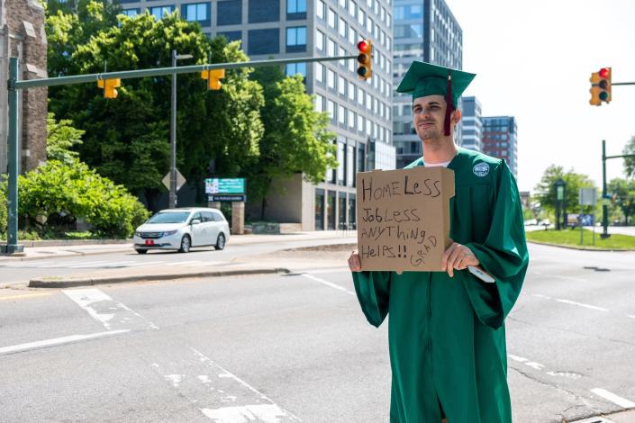 Michael Wilson, a recent MSU graduate, stands at Michigan and Grand River Avenues on May 15, 2023, hoping to raise money for housing and his phone plan.