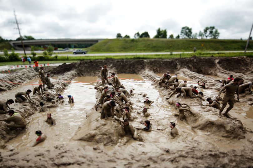 Participants climb through mud at a Tough Mudder event