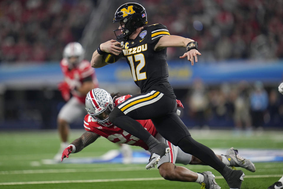 Missouri quarterback Brady Cook (12) runs next to Ohio State linebacker Steele Chambers during the first half of the Cotton Bowl NCAA college football game Friday, Dec. 29, 2023, in Arlington, Texas. (AP Photo/Julio Cortez)