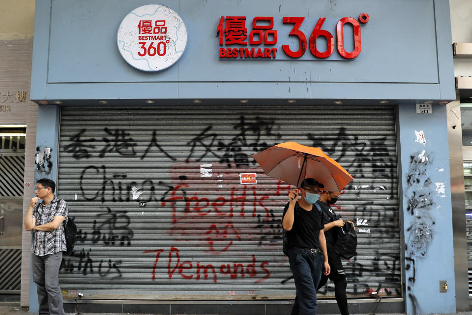 People walk past a shop painted by anti-government protesters in Hong Kong, Saturday, Oct. 12, 2019. The protests that started in June over a now-shelved extradition bill have since snowballed into an anti-China campaign amid anger over what many view as Beijing's interference in Hong Kong's autonomy that was granted when the former British colony returned to Chinese rule in 1997. (AP Photo/Kin Cheung)