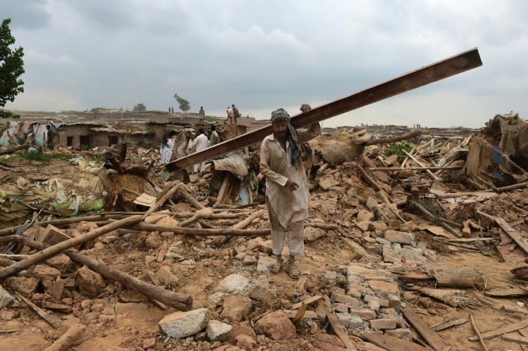 Pakistani men shift through debris of demolished houses during an operation to demolish their poverty-stricken neighbourhood in Islamabad on July 31, 2015