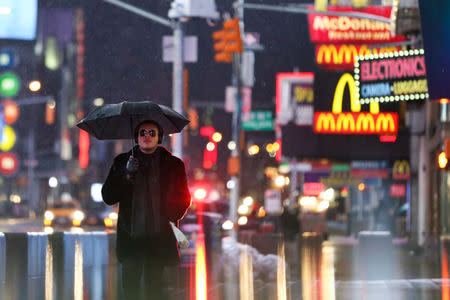 A man walks through the rain in Times Square in Manhattan, New York, U.S., March 7, 2018. REUTERS/Amr Alfiky