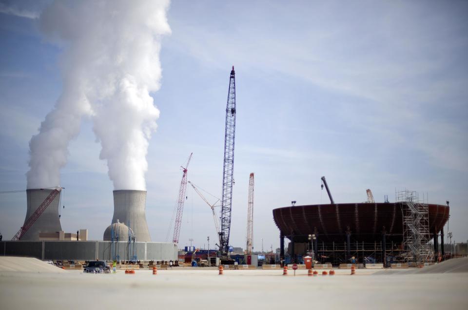 FILE - In this Feb. 15, 2012 file photo, cooling towers for units 1 and 2 are seen at left as the new reactor vessel bottom head for unit 3 stands under construction at right at the Vogtle nuclear power plant in Waynesboro, Ga. Vogtle initially estimated to cost $14 billion, has run into over $800 million in extra charges related to licensing delays. A state monitor has said bluntly that co-owner, Southern Co. can’t stick to its budget. The plant, whose first reactor was supposed to be operational by April 2016, is now delayed seven months.(AP Photo/David Goldman, File)