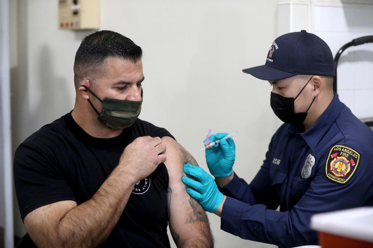 Los Angeles Fire Department Capt. Elliot Ibanez, left, receives the Moderna COVID-19 vaccine given by LAFD paramedic Anthony Kong at Station 4 on Monday, Dec. 28, 2020, in Los Angeles, Calif.