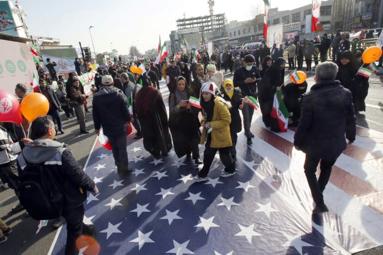 Unos iraníes pisan una gran bandera de Estados Unidos colocada en el suelo en Teherán para conmemorar el 45º aniversario de la Revolución Islámica, el 11 de febrero de 2024 (-)