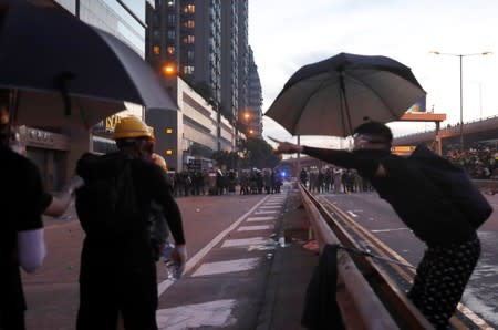 Demonstrators react as they face riot police during a protest against police violence in Hong Kong