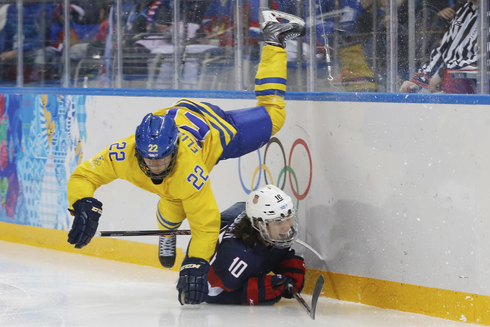 Emma Eliasson of Sweden trips over Meghan Duggan of the United States during the third period of the 2014 Winter Olympics women's semifinal ice hockey game at Shayba Arena, Monday, Feb. 17, 2014, in Sochi, Russia. (AP Photo/Petr David Josek)