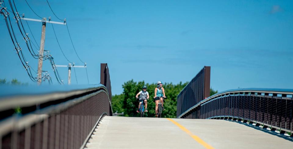 Kim Fleming, right, of Framingham, bicycled across the bridge crossing Rte. 30 on the Saxonville Branch of the Cochituate Rail Trail,  reaching from Framingham into Natick, July 7, 2022. 