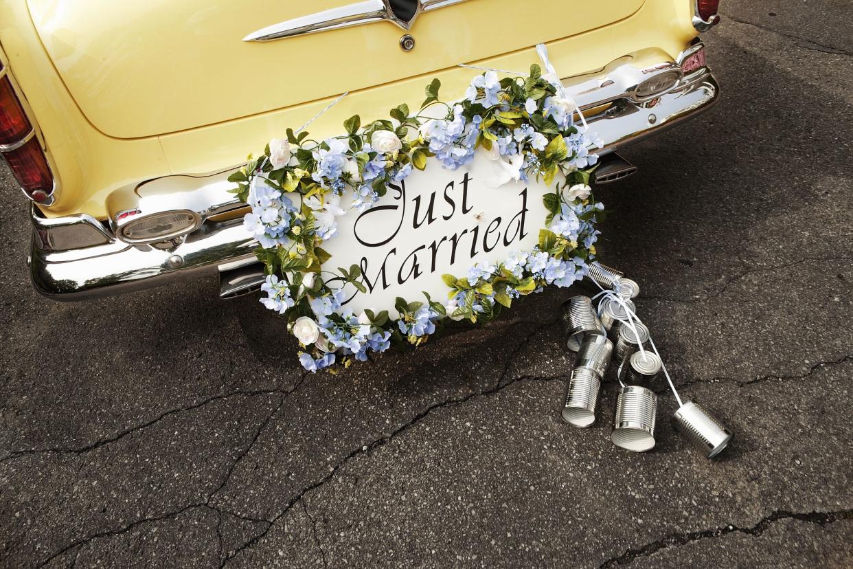 Bumper of limousine with just married sign and cans attached