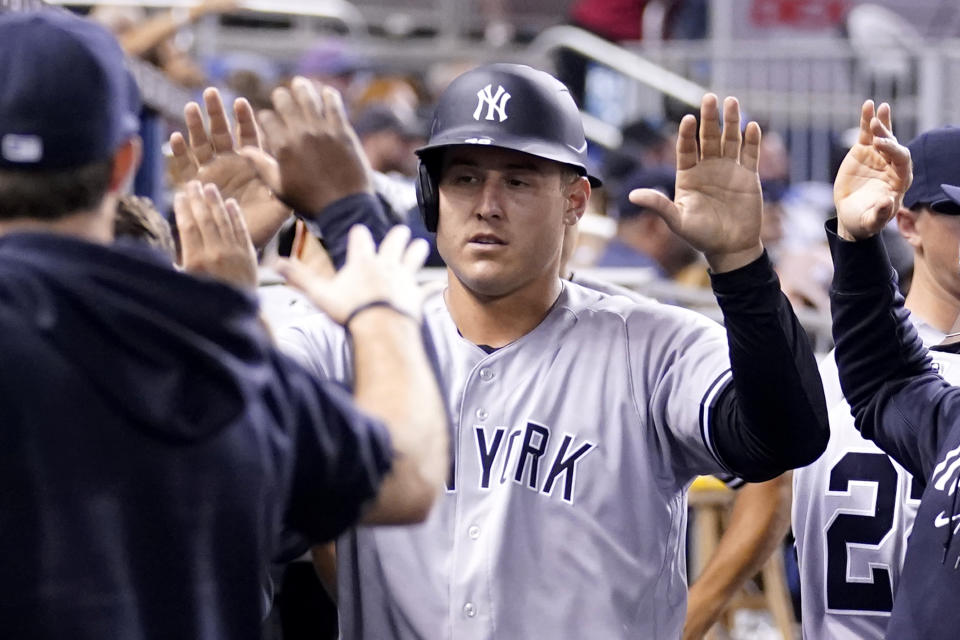 New York Yankees' Anthony Rizzo is congratulated in the dugout after scoring on a wild pitch by Miami Marlins reliever Anthony Bender during the fifth inning of a baseball game, Saturday, July 31, 2021, in Miami. (AP Photo/Lynne Sladky)