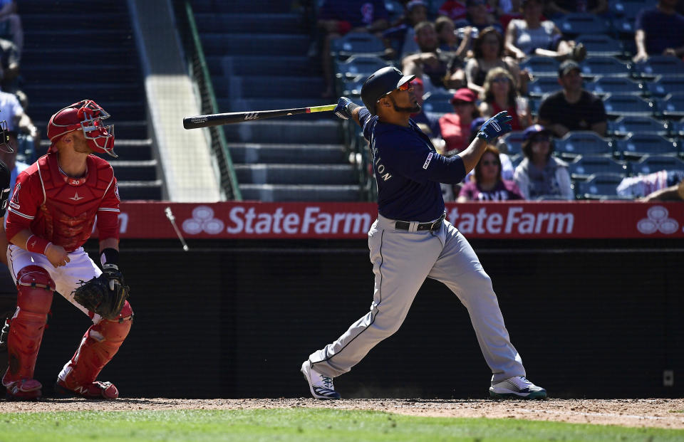 Seattle Mariners' Edwin Encarnacion, right, hits a two-run home run as Los Angeles Angels catcher Jonathan Lucroy watches during the seventh inning of a baseball game Sunday, June 9, 2019, in Anaheim, Calif. (AP Photo/Mark J. Terrill)