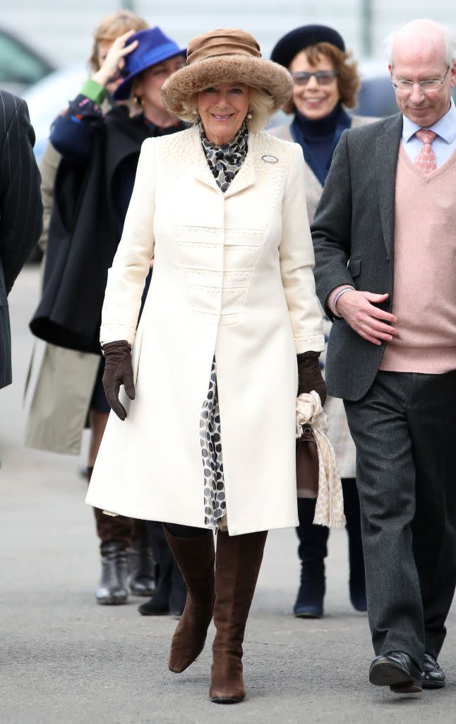 <p>The Duchess of Cornwall attended 'Ladies Day' at the Cheltenham Races wearing a structured white coat with intricate embellishments over a polka dot dress. She topped off the look with chocolate brown boots, gloves, and bag, a tan fur-trimmed hat, and pearl drop earrings. </p>