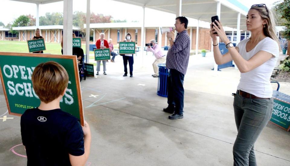 Emily Grace Rainey uses her phone to document a demonstration against pandemic precautions before an Oct. 12, 2020 meeting of the Moore County Board of Education.