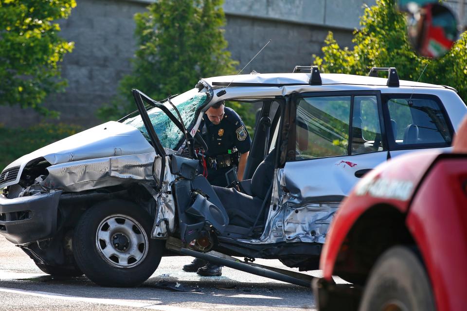 A New Bedford police officer looks into the SUV which was struck by the red truck in the foreground at the intersection of Route 18 and Elm Street in New Bedford.