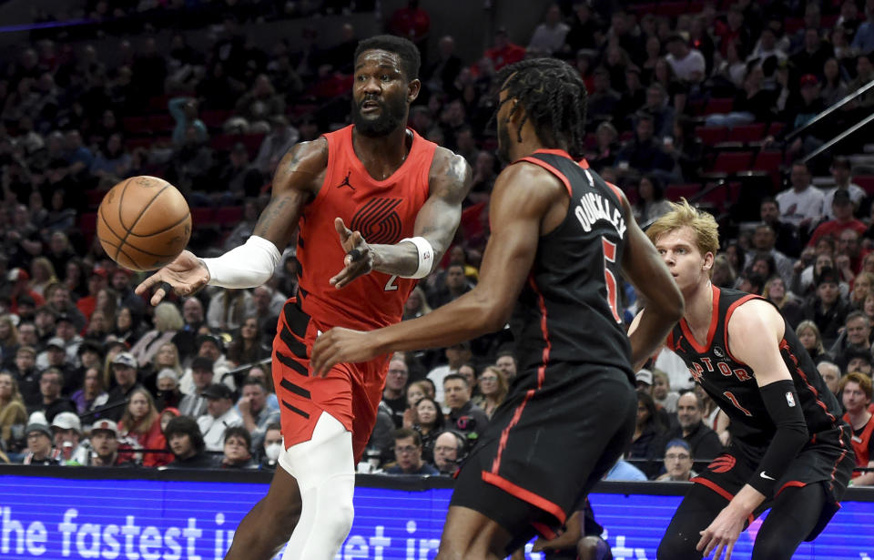 Portland Trail Blazers center Deandre Ayton, left, passes the ball as Toronto Raptors guard Immanuel Quickley, center, and guard Gradey Dick defend during the first half of an NBA basketball game in Portland, Ore., Saturday, March 9, 2024. (AP Photo/Steve Dykes)