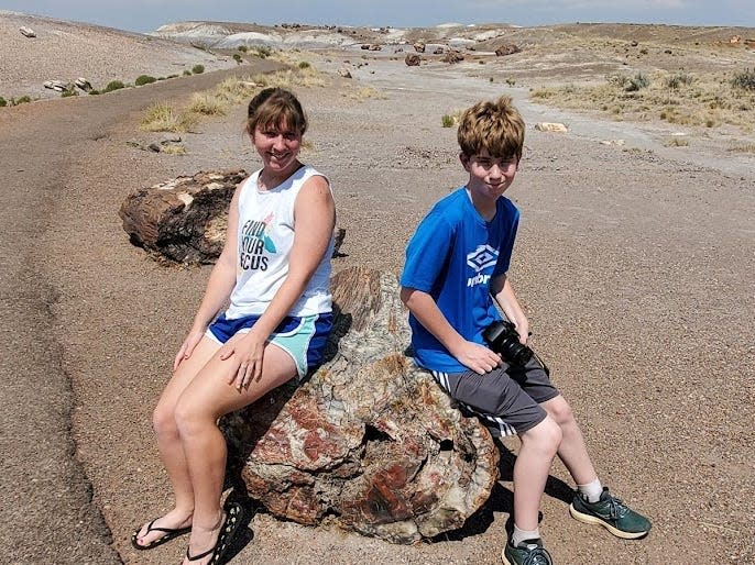 Two kids sitting on piece of petrified wood in Petrified Forest