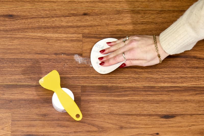 overhead shot of someone sanding down a patched hardwood floor.