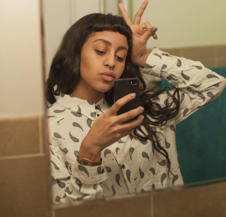 A young woman taking a selfie in the mirror