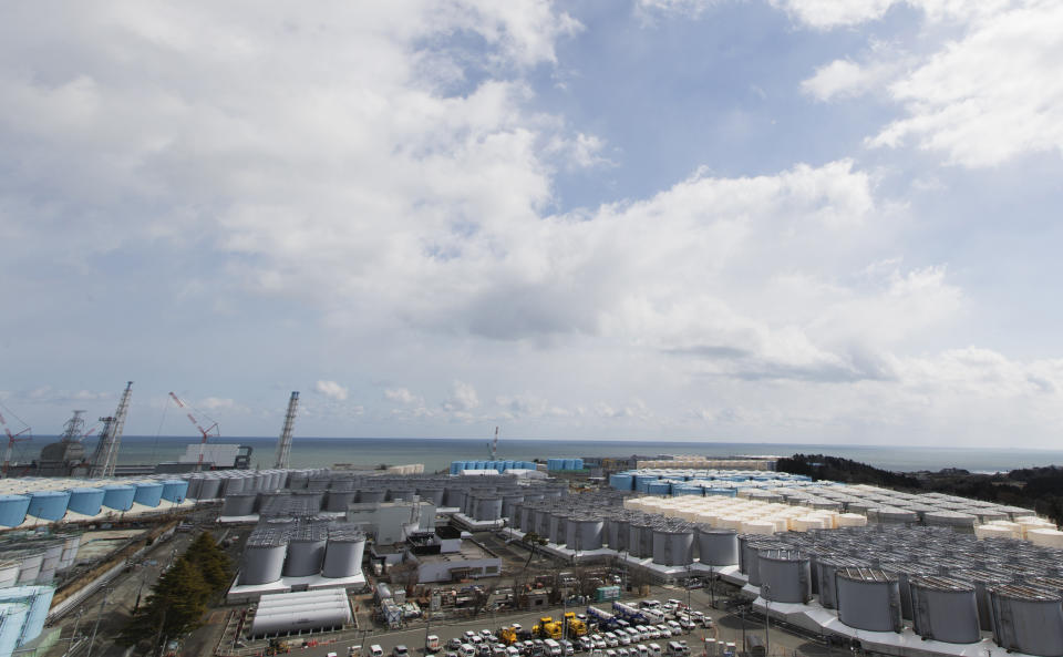 This photo shows tanks (in gray, beige and blue) of storing water that was treated but still radioactive after it was used to cool down spent fuel at the Fukushima Daiichi nuclear power plant in Okuma town, Fukushima prefecture, northeastern Japan, Saturday, Feb. 27, 2021. The reactors of the Unit 3, lower left, and 4 are seen by the ocean. (AP Photo/Hiro Komae)