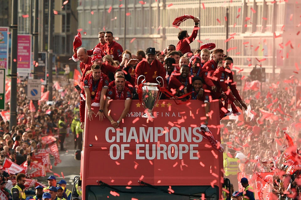 TOPSHOT - Liverpool's German manager Jurgen Klopp (C) holds the European Champion Clubs' Cup trophy during an open-top bus parade around Liverpool, north-west England on June 2, 2019, after winning the UEFA Champions League final football match between Liverpool and Tottenham. - Liverpool's celebrations stretched long into the night after they became six-time European champions with goals from Mohamed Salah and Divock Origi to beat Tottenham -- and the party was set to move to England on Sunday where tens of thousands of fans awaited the team's return. The 2-0 win in the sweltering Metropolitano Stadium delivered a first trophy in seven years for Liverpool, and -- finally -- a first win in seven finals for coach Jurgen Klopp. (Photo by Oli SCARFF / AFP)        (Photo credit should read OLI SCARFF/AFP/Getty Images)