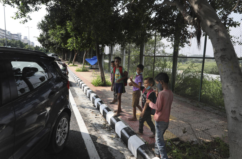 Children wave goodbye to Veena Gupta as she leaves after conducting a class on a sidewalk in New Delhi, India, on Sept. 3, 2020. Veena and her husband are conducting free classes for underprivileged children on a sidewalk in New Delhi with the goal to keep them learning and not left behind when schools reopen. As most schools in India remain shut since late March when the country imposed a nationwide lockdown to curb the spread of COVID-19, many switched to digital learning and taking classes online. (AP Photo/Manish Swarup)