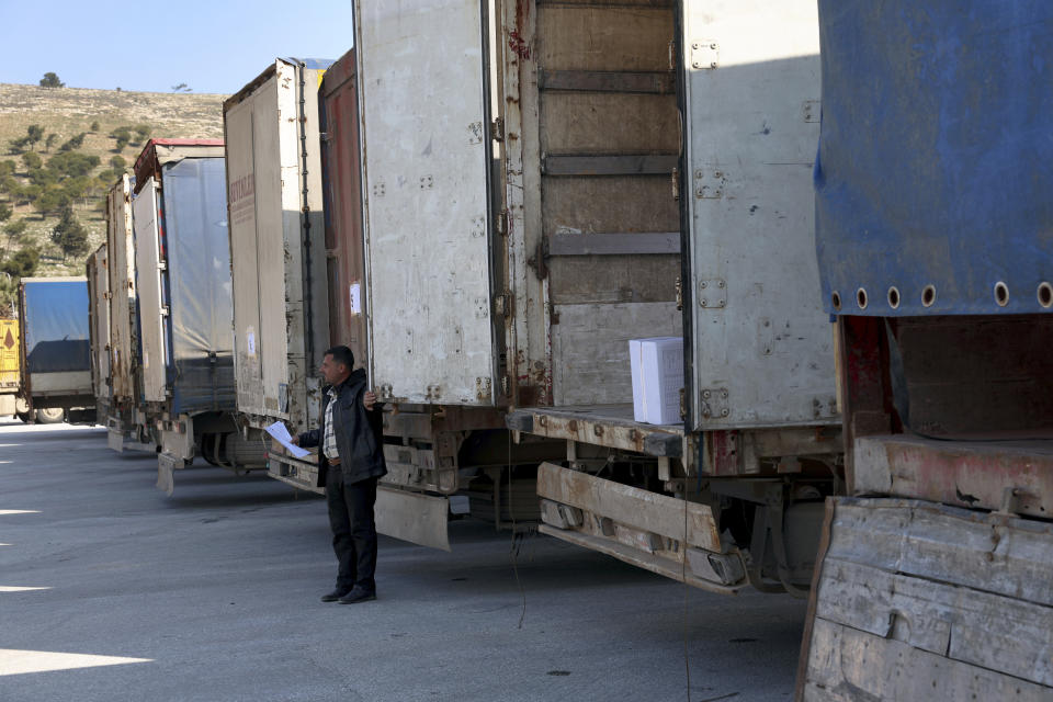 A border customs official inspects trucks loaded with UN humanitarian aid for Syria following a devastating earthquake reach the Bab al-Hawa border crossing with Turkey, Idlib province, Syria, Friday, Feb. 10, 2023. Rescuers pulled several people alive from the shattered remnants of buildings on Friday, some who survived more than 100 hours trapped under crushed concrete in the bitter cold after a catastrophic earthquake slammed Turkey and Syria. (AP Photo/Ghaith Alsayed)