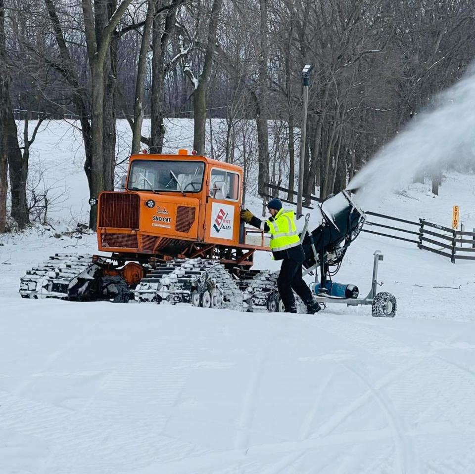 As a snow gun blankets the slopes at Swiss Valley Ski & Snowboard Area in Jones, a staff member works with the resort's 1978 groomer to prepare for opening. Swiss Valley also has a more modern groomer.