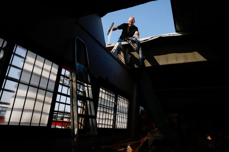 A member of staff from Hollandia International works to fix damage to the roof of the company warehouse facility that was caused by a rocket that was launched from the Gaza Strip into Sderot