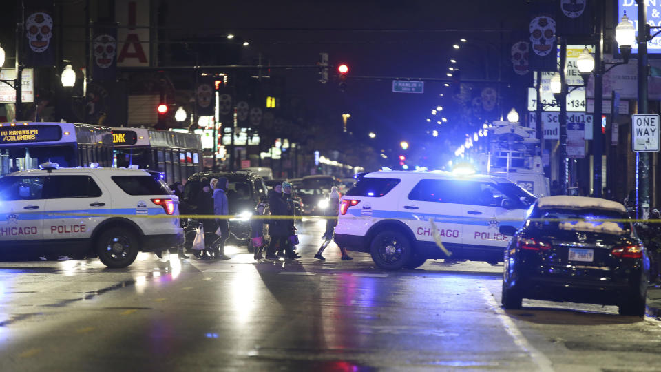 Trick-or-treaters walk past a crime scene in the 3700 block of West 26th Street, where a 7-year-old girl was shot while trick-or-treating Thursday, Oct. 31, 2019, in Chicago. A 7-year-old girl out trick-or-treating in a bumblebee outfit was critically injured Thursday night during a shooting on Chicago's West Side. (John J. Kim/Chicago Tribune via AP)