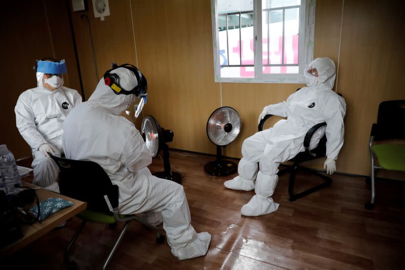 FILE PHOTO: Medical staff in protective gear take a break at a facility of a 'drive-thru' testing center for the novel coronavirus disease of COVID-19 in Yeungnam University Medical Center in Daegu