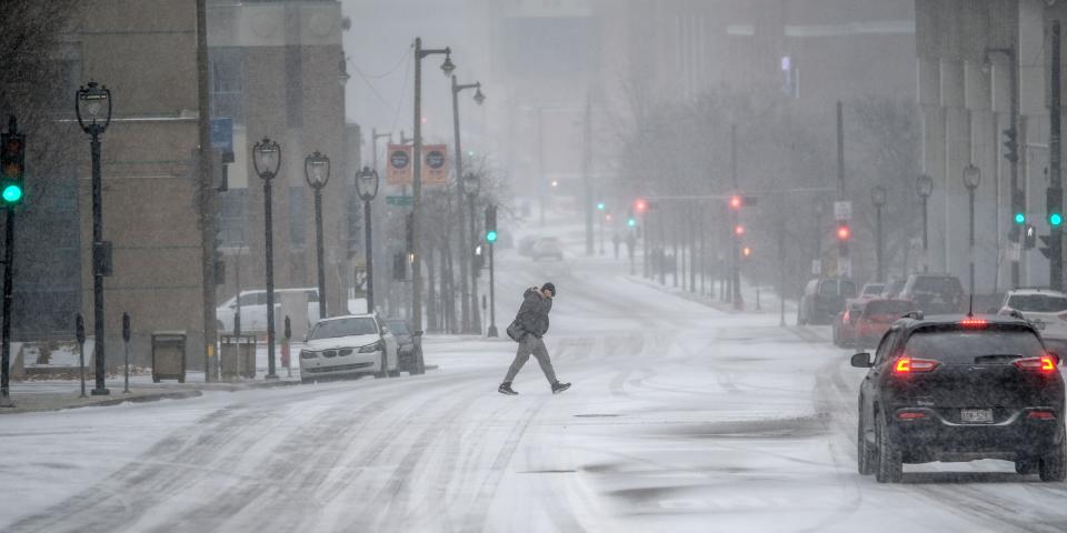 People commute in downtown Milwaukee as Wisconsin braces for a winter storm that in the coming days could bring blizzard conditions, causing possible power outages, and make holiday travel conditions dangerous.