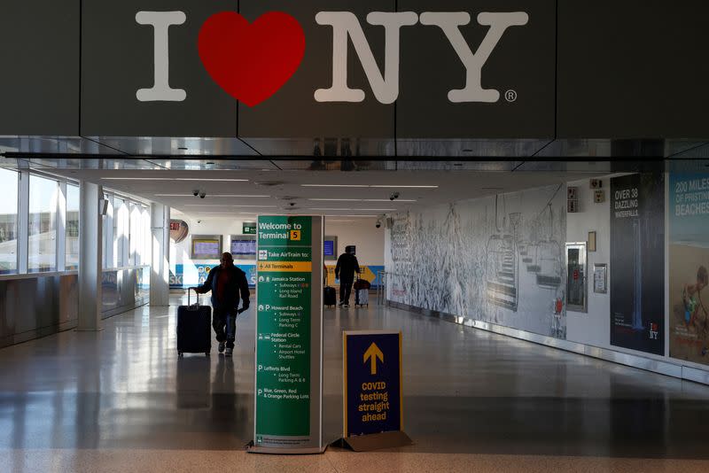 FILE PHOTO: Air travellers wearing a protective face masks, amid the coronavirus disease (COVID-19) pandemic, at JFK International airport in New York