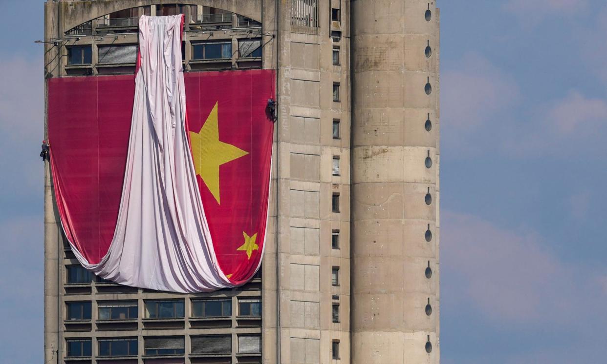<span>Workers install a giant Chinese national flag on a skyscraper in Belgrade.</span><span>Photograph: Darko Vojinović/AP</span>