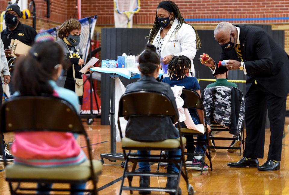 Alabama State University President Quinton Ross, right, helps distract Jaylie Pierre as she gets her COVID-19 vaccine during a Vaccine Clinic for students, aged 5-11, on the ASU campus in Montgomery, Ala., on Friday January 21, 2022. The clinic was put on in partnership between Alabama State University, Montgomery Public Schools and the Alabama Department of Public Health. 