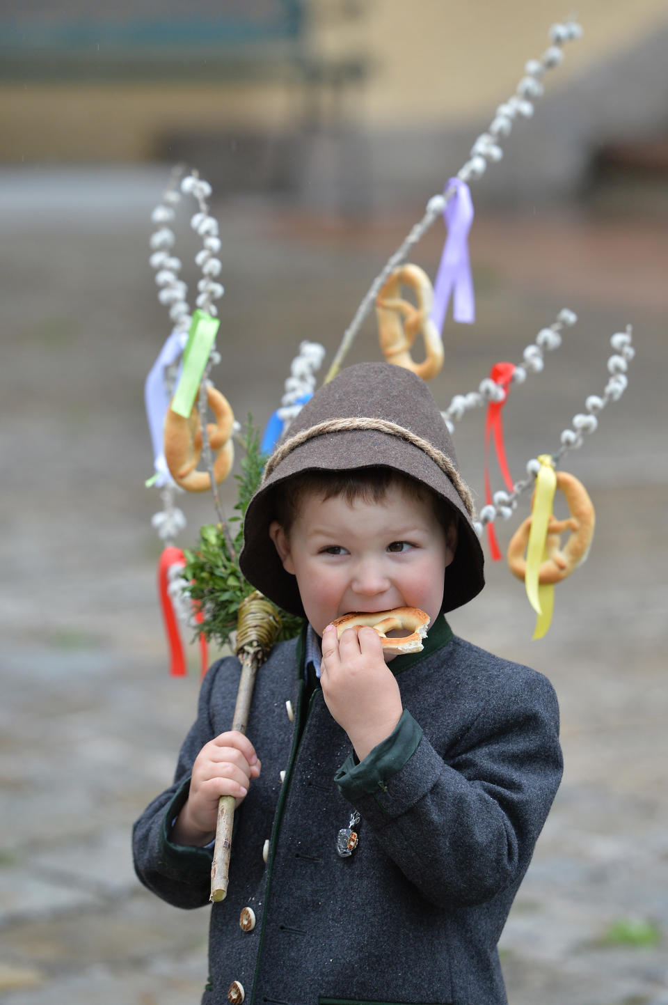 The three years old Thomas Haitzmann eats a "Palmbrezeln" after a Palm Sunday procession in Lofer, Austrian province of Salzburg, Sunday, April 13, 2014. Palm Sunday opens the Holy Week which ends with Easter Sunday, the most important Christian holiday. (AP Photo/Kerstin Joensson)