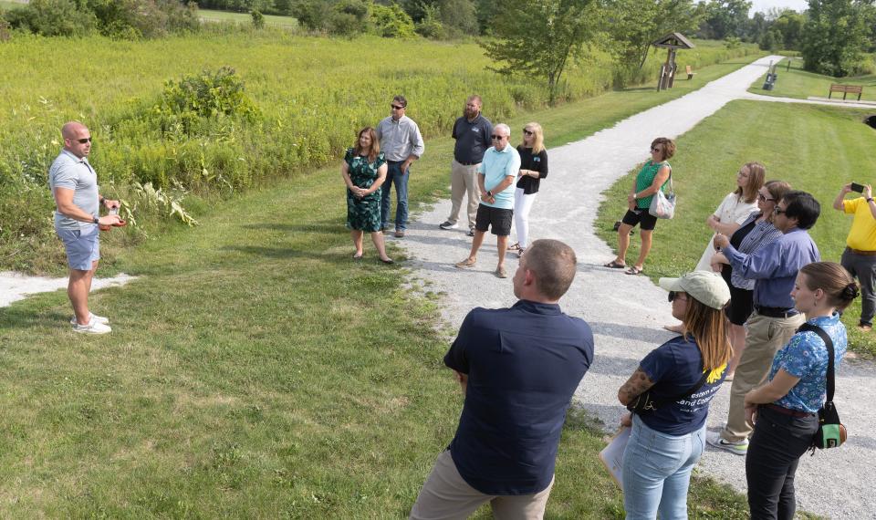 Plain Township Trustee Scott Haws, left, speaks before a ribbon cutting at Veterans Park to mark Plain Township's purchase in July of nearly 20 acres of an adjoining prairie and wetland habitat on Schneider Street NE.
