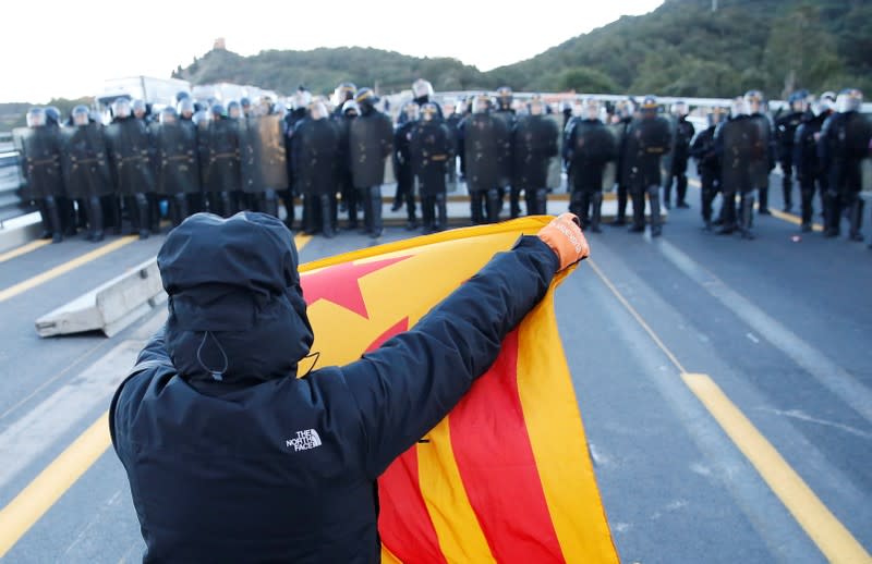 A man holds an Estelada (Catalan separatist flag) in front of French police officers at the AP-7 highway