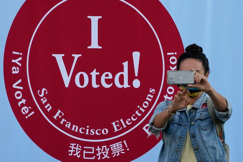 A woman takes a photo in front of an I Voted sign at a San Francisco Department of Elections voting center in San Francisco, Monday, Nov. 2, 2020, ahead of Election Day.