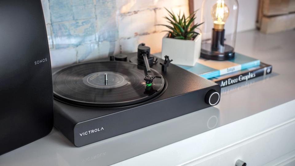 Victrola Stream Onyx record player on a side table next to a Sonos speaker
