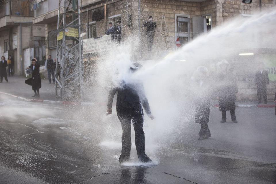 <p>Ein ultraorthodoxer Jude wird bei einer Demonstration gegen die israelische Wehrpflicht von einem Wasserwerfer getroffen. (Bild: Oded Balilty/AP) </p>