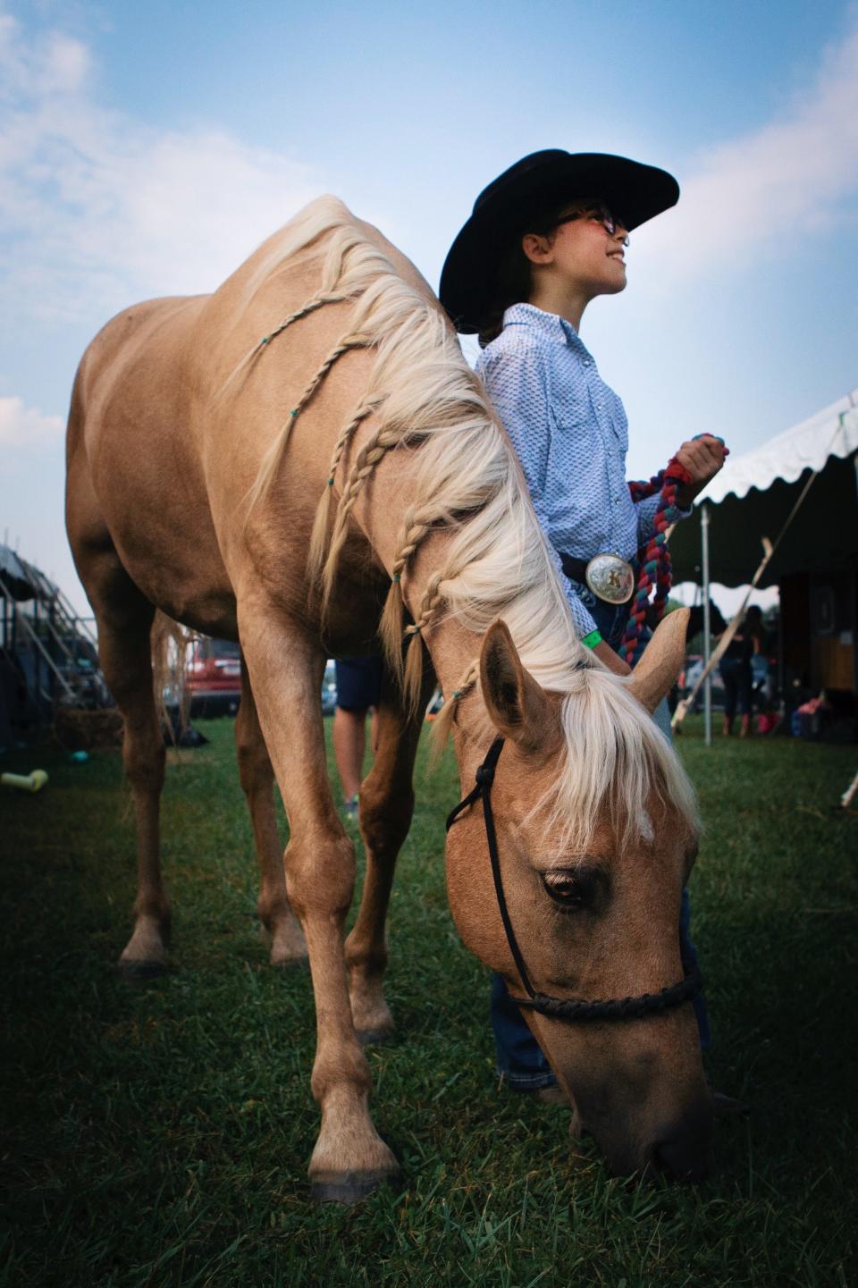 Irelyn Cotton, 9, poses for a portrait with her horse Charlie at the Hamilton County 4-H Community Fair in 2019. Cotton braided the mane of her horse before a competition.