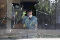 A worker vacuums broken glass from store front in downtown Louisville, Ky. , Saturday, May 30, 2020. The store was damaged Friday evening during a protest over the deaths of George Floyd and Breonna Taylor. (AP Photo/Darron Cummings)