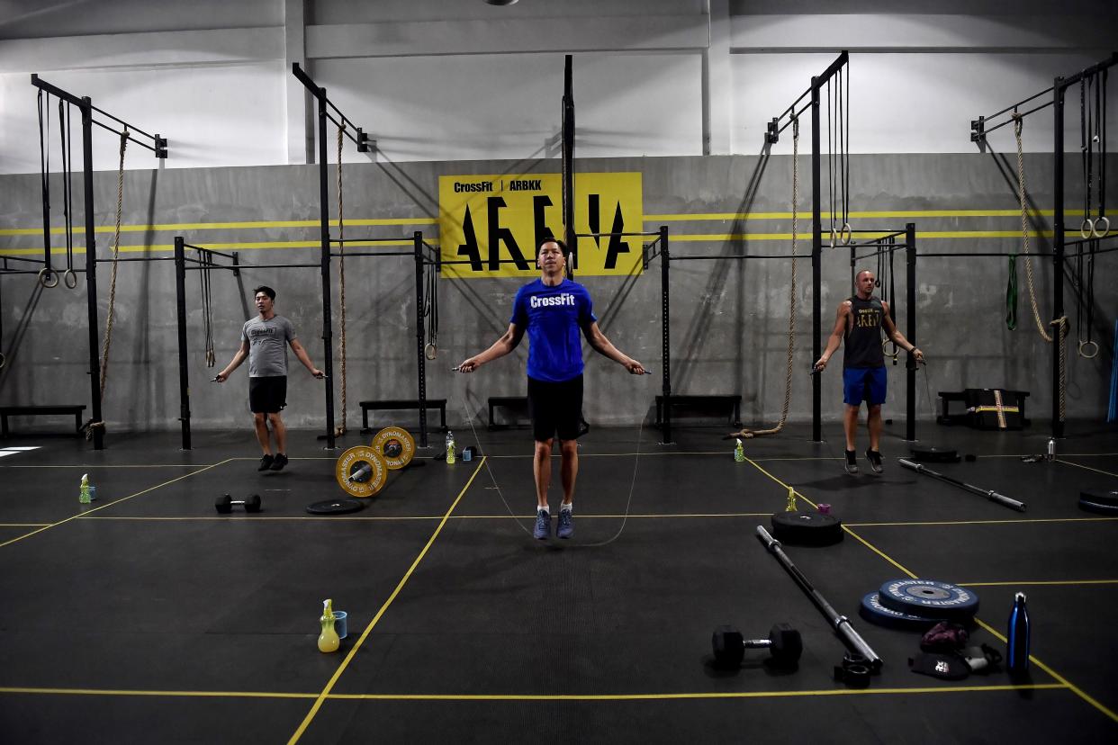 Gym enthusiasts exercise whilst maintaining distance from each other at CrossFit Arena Bangkok, during their first week of reopening following closure of physical wellness centers after authorities lifted some measures of restrictions to halt the spread of the COVID-19 coronavirus in Bangkok on May 20, 2020. (Photo by Lillian SUWANRUMPHA / AFP) (Photo by LILLIAN SUWANRUMPHA/AFP via Getty Images)