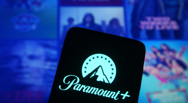 PARA stock: the Paramount plus logo on a phone in front of a screen displaying various Paramount TV shows and movies